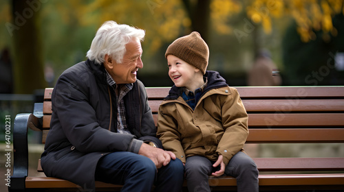 Happy grandson talking to his grandfather while sit in public park
