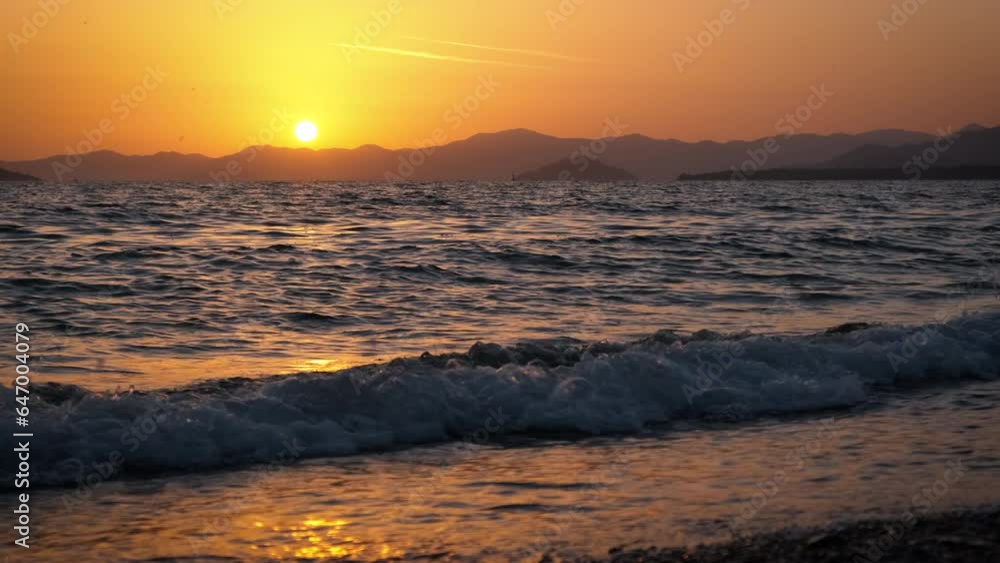 Orange sun silhouette by foaming night ocean. A view of foaming ocean silhouette during red sunset in summer. Orange sun silhouette by foaming night ocean. A view of foaming ocean silhouette during red sunset in summer.