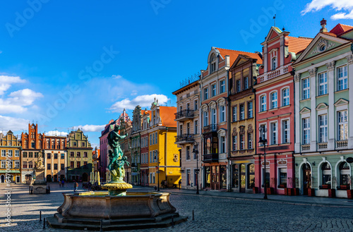 Fountain of Neptune surrounded by picturesque townhouses on central Market Square of Polish city of Poznan in sunny spring day