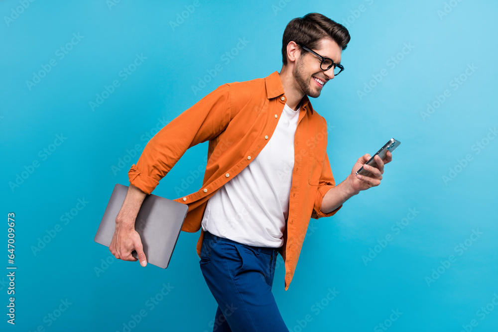 Fototapeta premium Profile photo of handsome manager man walking hold netbook use smart phone texting isolated on blue color background