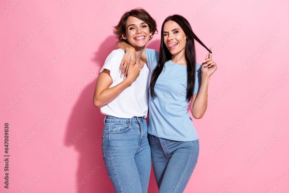 Photo of attractive young lady playing hair wearing t shirt denim jeans playful chics lesbians isolated on pastel pink color background Photo of attractive young lady playing hair wearing t shirt denim jeans playful chics lesbians isolated on pastel pink color background