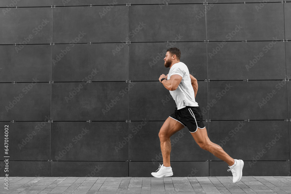 Young man running near building outdoors. Space for text Young man running near building outdoors. Space for text