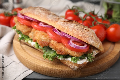 Delicious sandwich with schnitzel on grey wooden table