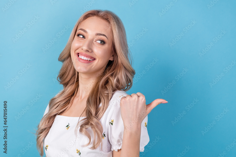 Photo of dreamy sweet lady wear white blouse looking pointing thumb back empty space isolated blue color background Photo of dreamy sweet lady wear white blouse looking pointing thumb back empty space isolated blue color background