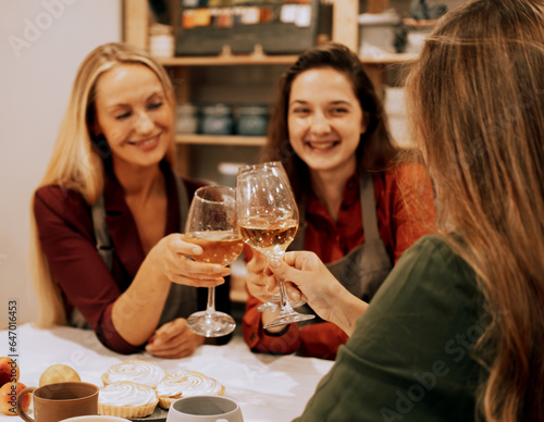 Three cheerful young women friends are having fun in a ceramic workshop. They drink wine and joke  have fun.