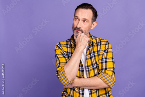 Portrait of ponder pensive person dressed checkered shirt look at intersting offer empty space isolated on violet color background photo