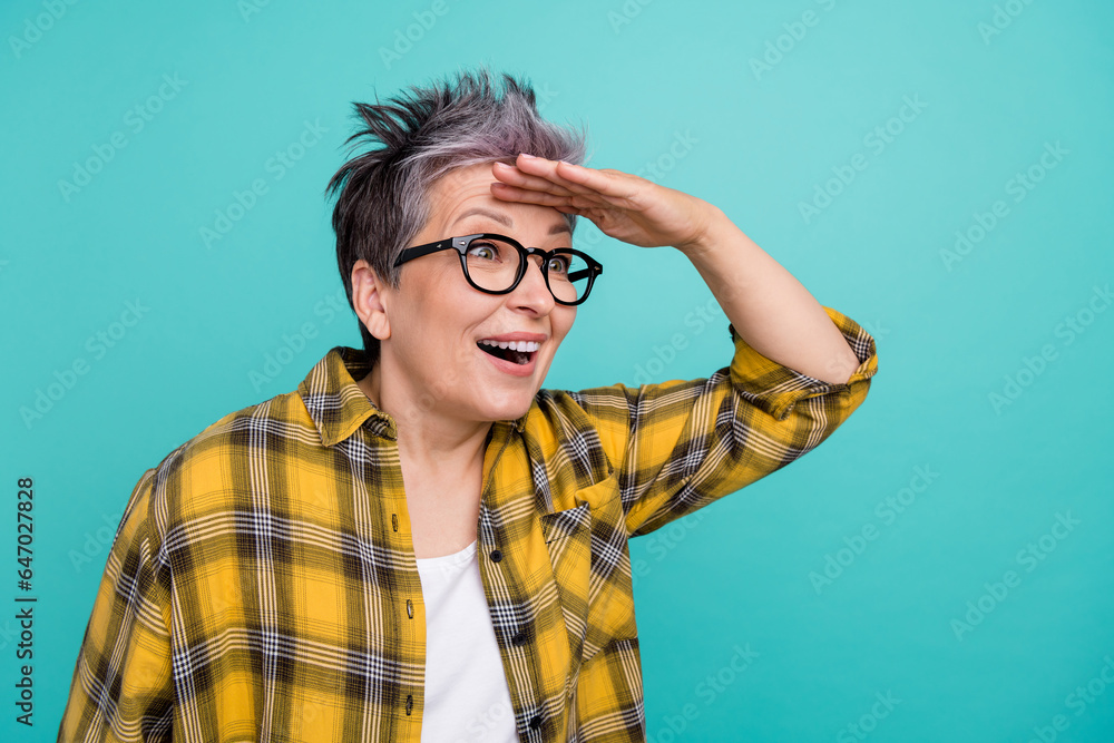 Photo of attractive retired woman hand forehead search dressed stylish checkered yellow clothes isolated on aquamarine color background Photo of attractive retired woman hand forehead search dressed stylish checkered yellow clothes isolated on aquamarine color background