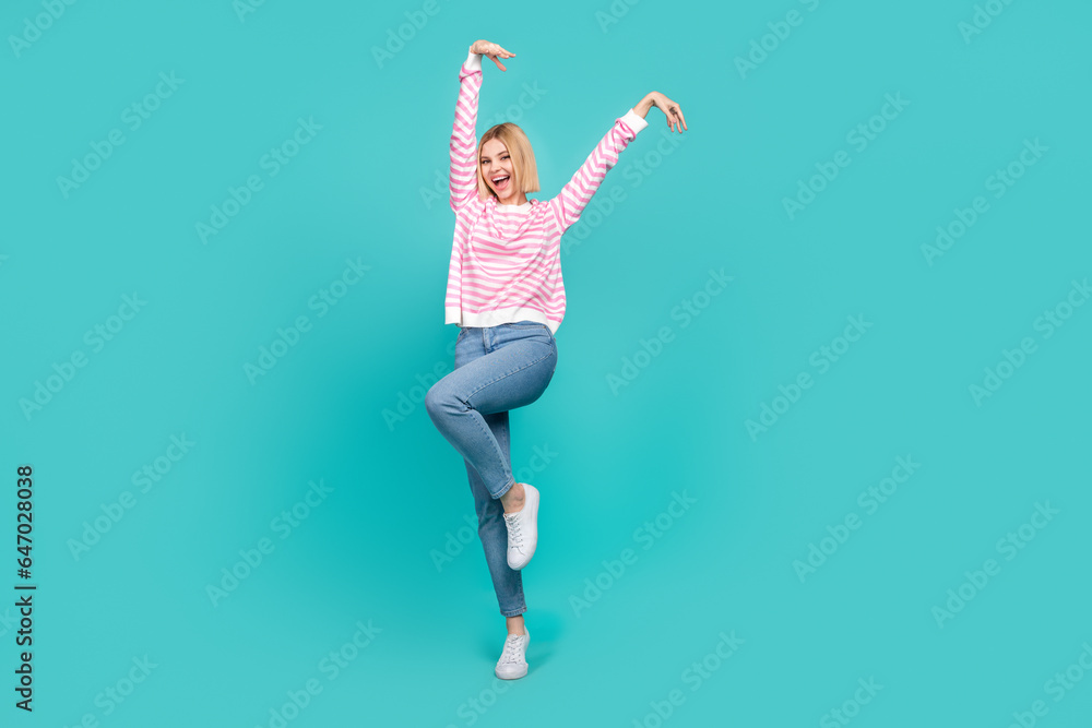 Full length photo of funky adorable girl dressed striped sweater smiling having fun isolated teal color background Full length photo of funky adorable girl dressed striped sweater smiling having fun isolated teal color background