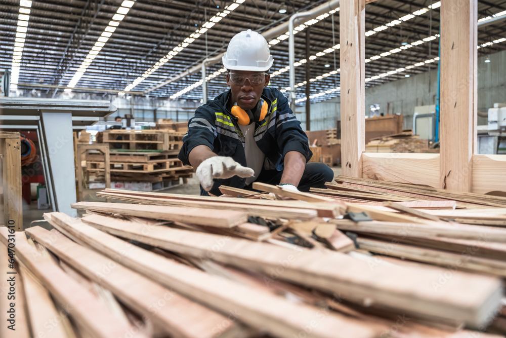 Black carpenter man working with plank wood in wood factory 