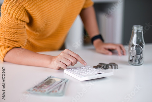 Close up asian women is keeping a record of her income and expenses, she plans her finances by using his monthly savings to buy funds to make it grow faster. Concept of saving money for investment