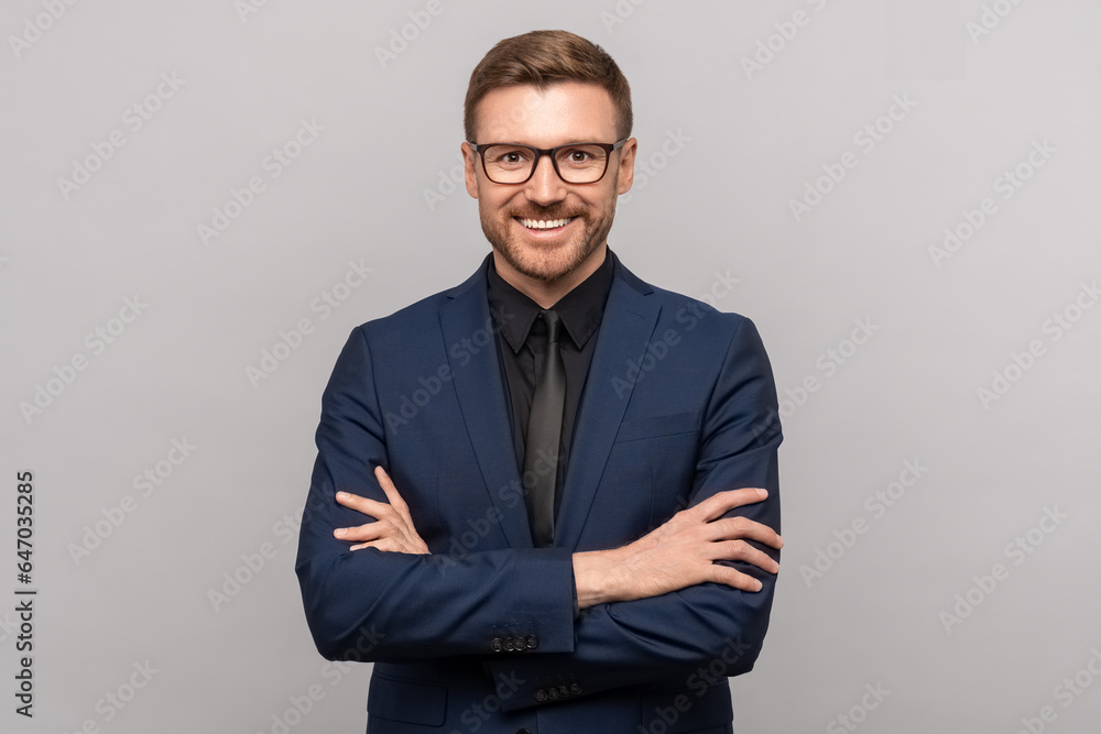 Portrait of happy successful confident businessman in suit with crossed arms on chest smiling looking at camera on grey background. Man entrepreneur in eyeglasses on advertisement poster, banner. - obrazy, fototapety, plakaty 