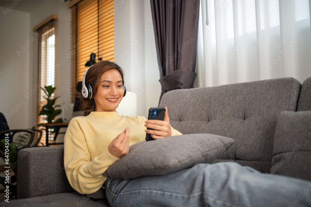 Obraz premium Woman wearing headphones and listening to music and singing happy at home on vacation.