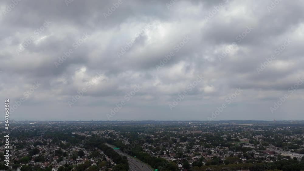 An aerial hyperlapse over a highway on Long Island, New York on a cloudy day. The drone camera dolly in as the clouds roll by, planes fly by from right to left and cars drive by below. An aerial hyperlapse over a highway on Long Island, New York on a cloudy day. The drone camera dolly in as the clouds roll by, planes fly by from right to left and cars drive by below.