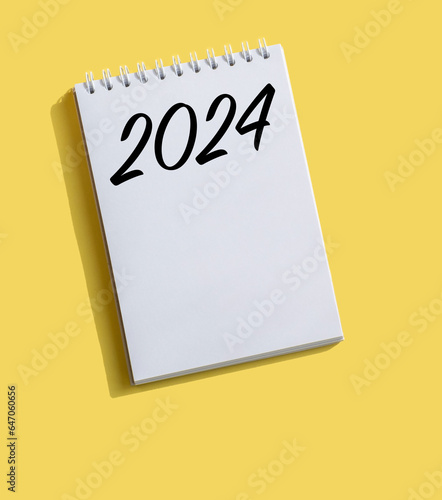 New Year 2024 written on note paper on a bright yellow background. Concept in business. Plans for the new year. Resolutions, plan, goals, action, checklist, idea concept