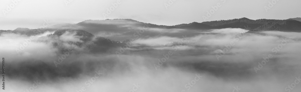 A thick fog covered the mountains, black and white landscape, panorama