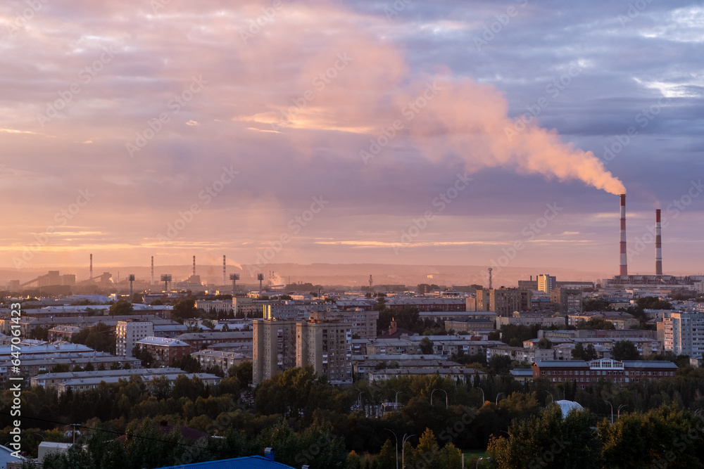 Beautiful urban area with houses and boiler room at sunset. View of the big city from above. Smoking chimneys of boiler rooms on the background of the cityscape