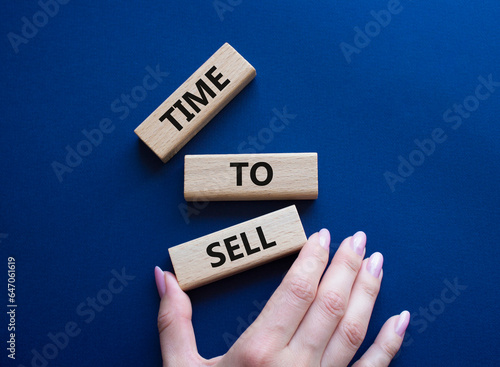 Time to Sell symbol. Concept words Time to Sell on wooden blocks. Businessman hand. Beautiful deep blue background. Business and Time to Sell concept. Copy space.