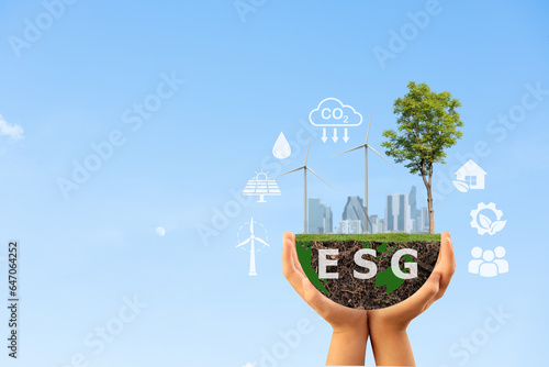 Two hands holding the earth with the letters ESG ,tree ,wind turbine and icons on nature background.Investment concept.