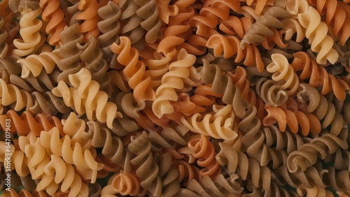 Closeup shot of many colorful pasta spirals background. Advertising area, template.