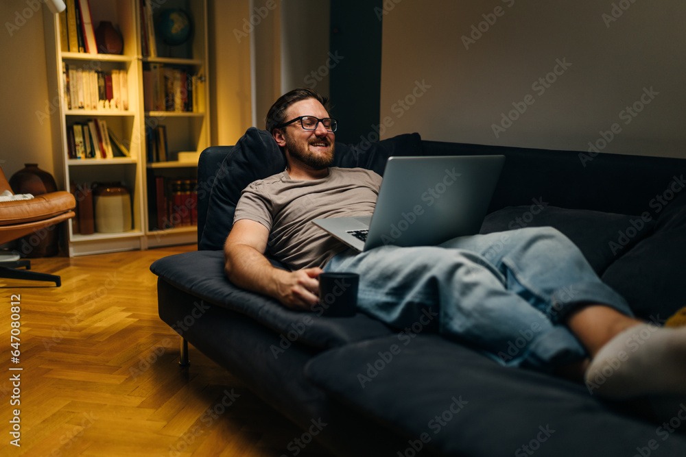 Caucasian man watching a comedy movie alone at home.