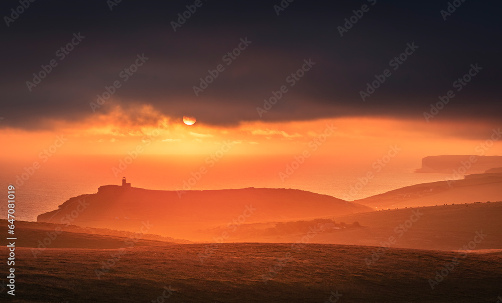 Dramatic skies and sunset behind Belle Tout lighthouse from the cliff edge of Beachy Head on the south downs east Sussex coast south east England UK