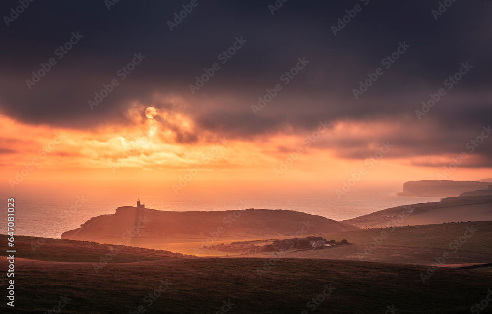 Dramatic skies and sunset behind Belle Tout lighthouse from the cliff edge of Beachy Head on the south downs east Sussex coast south east England UK