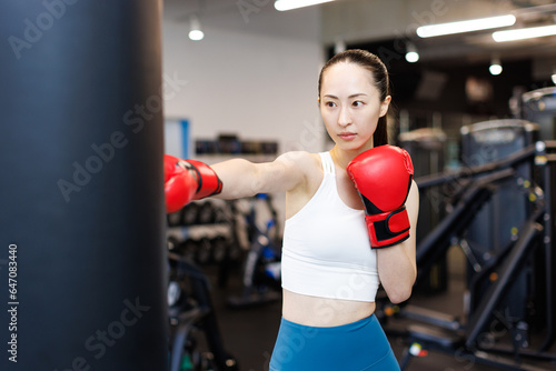 ボクシンググローブとパンチングバッグでトレーニングする若いアジアの女性