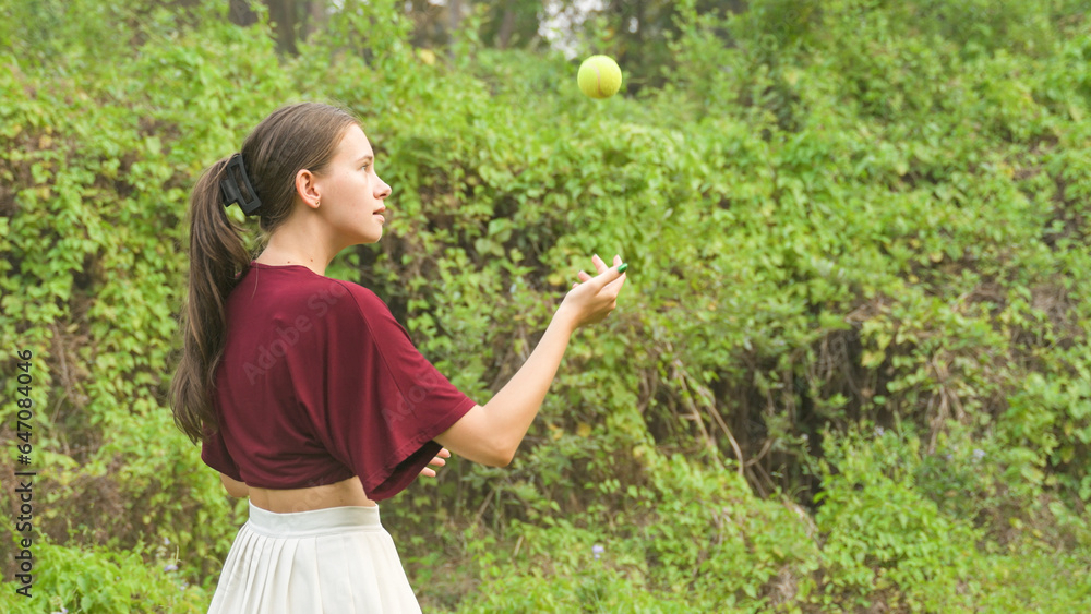 young woman juggles tennis balls against the backdrop of bushes young woman juggles tennis balls against the backdrop of bushes