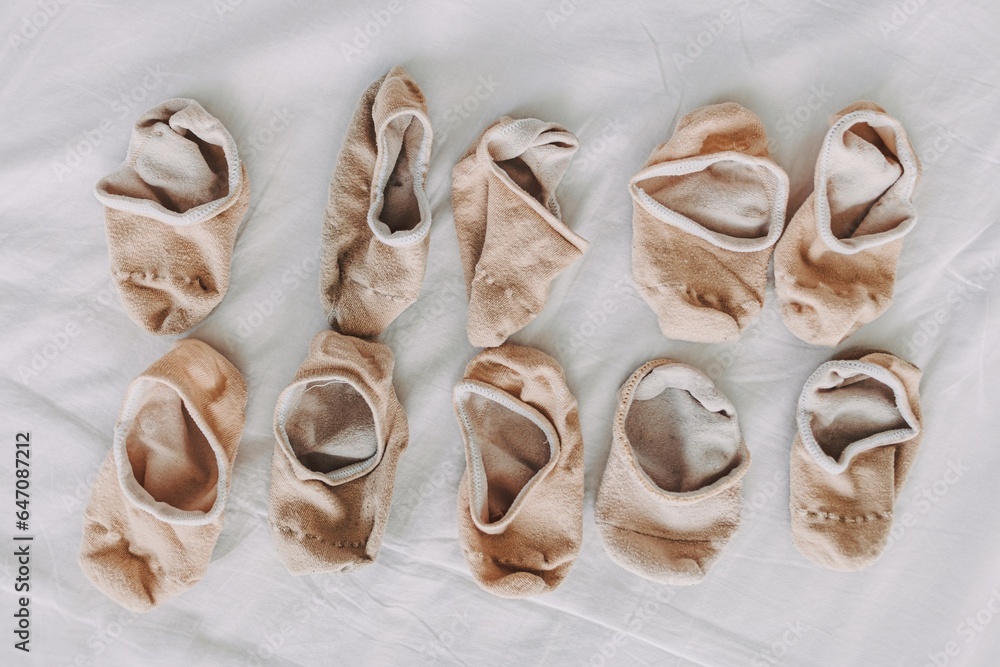 Fototapeta premium Pile and pairs of short socks arranged on white sheet bed.