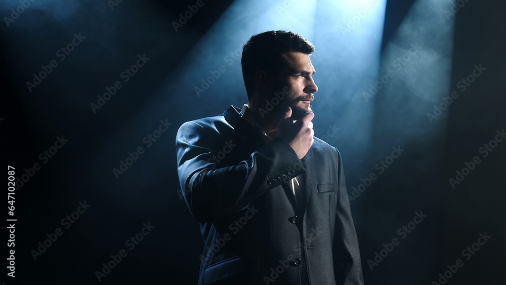 Attractive businessman posing stylishly against dark background