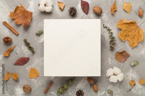 Greeting card mockup with autumn leaves on concrete background, top view