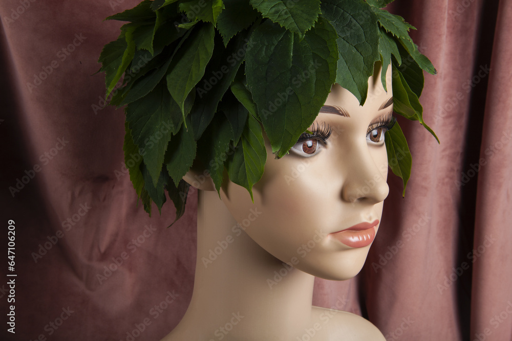 a display mannequin wearing hair of leaves on pink velvet background a display mannequin wearing hair of leaves on pink velvet background
