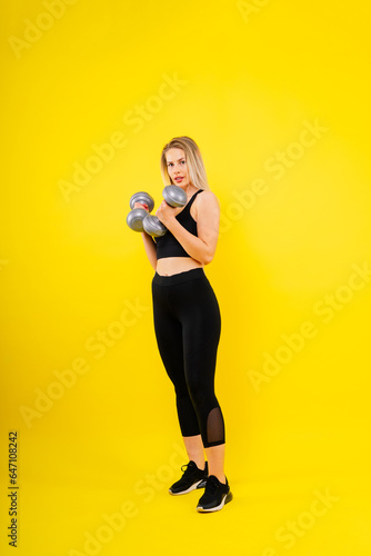 Perfect sporty female working out with dumbbells. Photo of woman in sportswear, studio