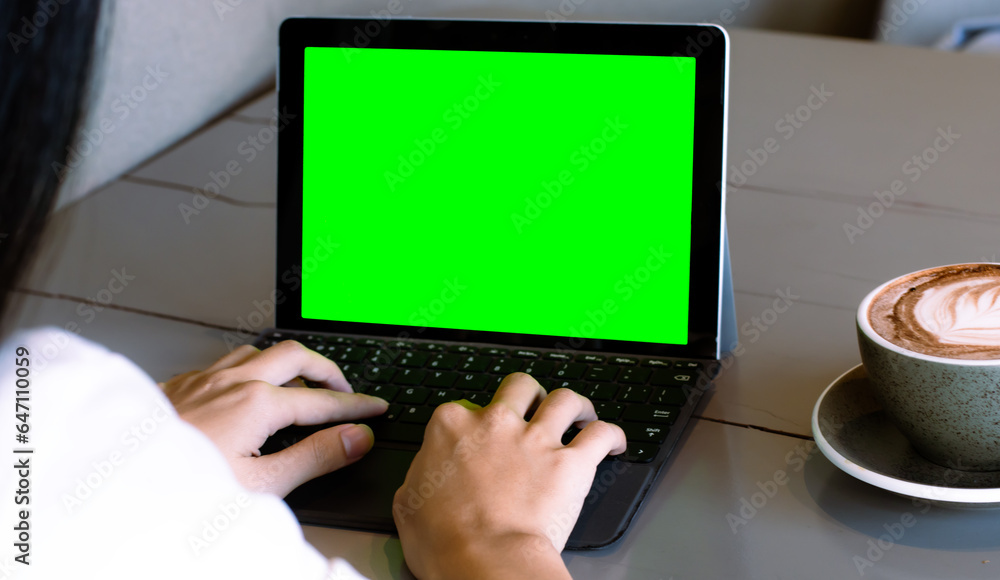 Close up of freelencer using laptop computer with mock up green screen chroma key display in cafe. Close up of freelencer using laptop computer with mock up green screen chroma key display in cafe.