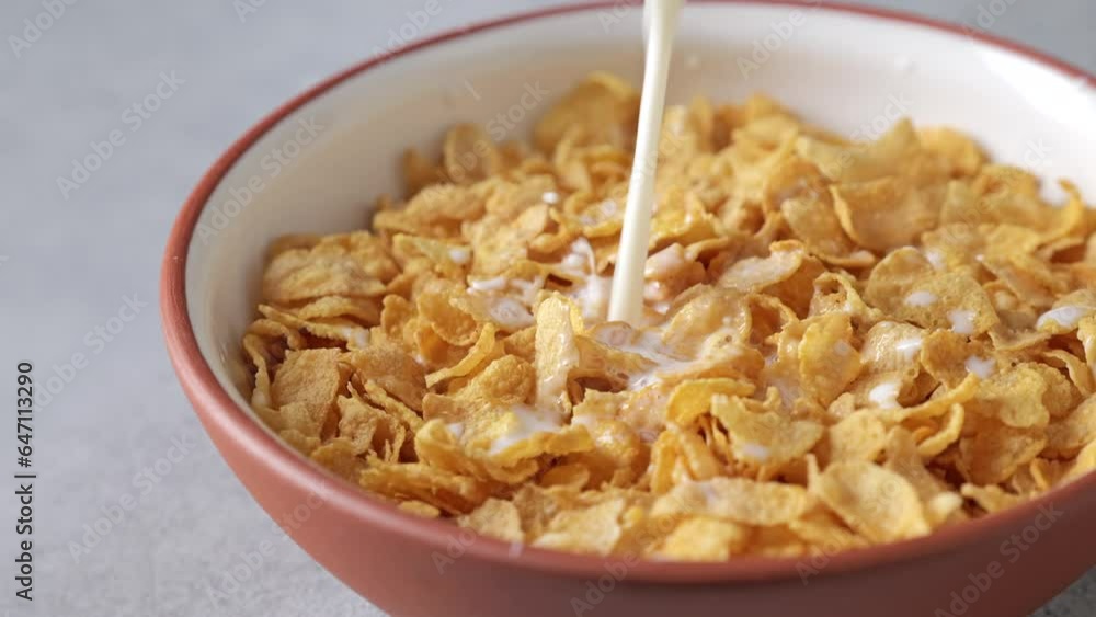 Milk is poured into a bowl of organic corn flake. Milk is poured into a bowl of organic corn flake.