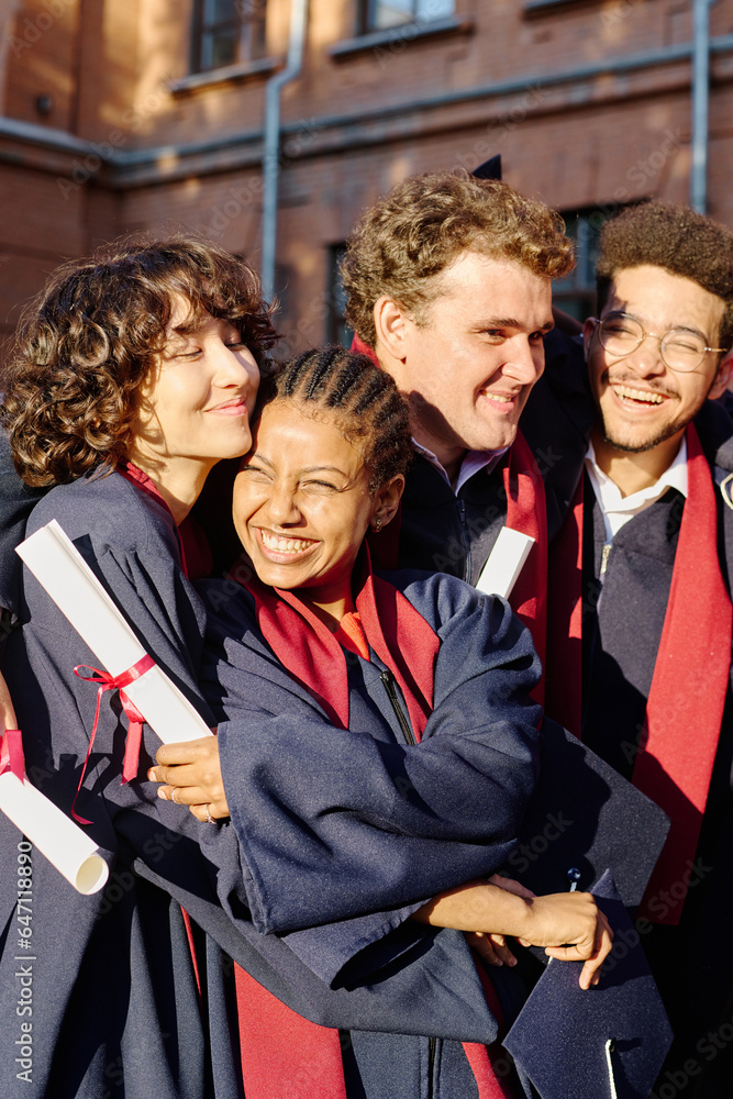 Obraz premium Vertical image of happy students embracing each other, they graduating from university