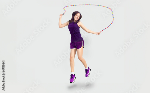 happy asian woman in sport wear doing rope jumping for exercise on isolated background © Yanukit