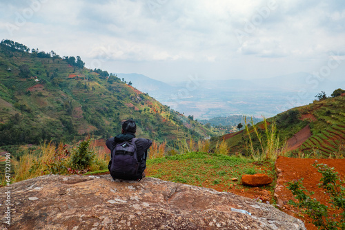 View of a hiker sitting on a rock at a scenic view point against valley at Uluguru Mountains in Tanzania