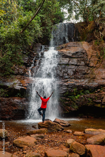 A hiker doing a yoga pose standing nest to a waterfall at Choma Waterfall in Uluguru Mountains, Tanzania