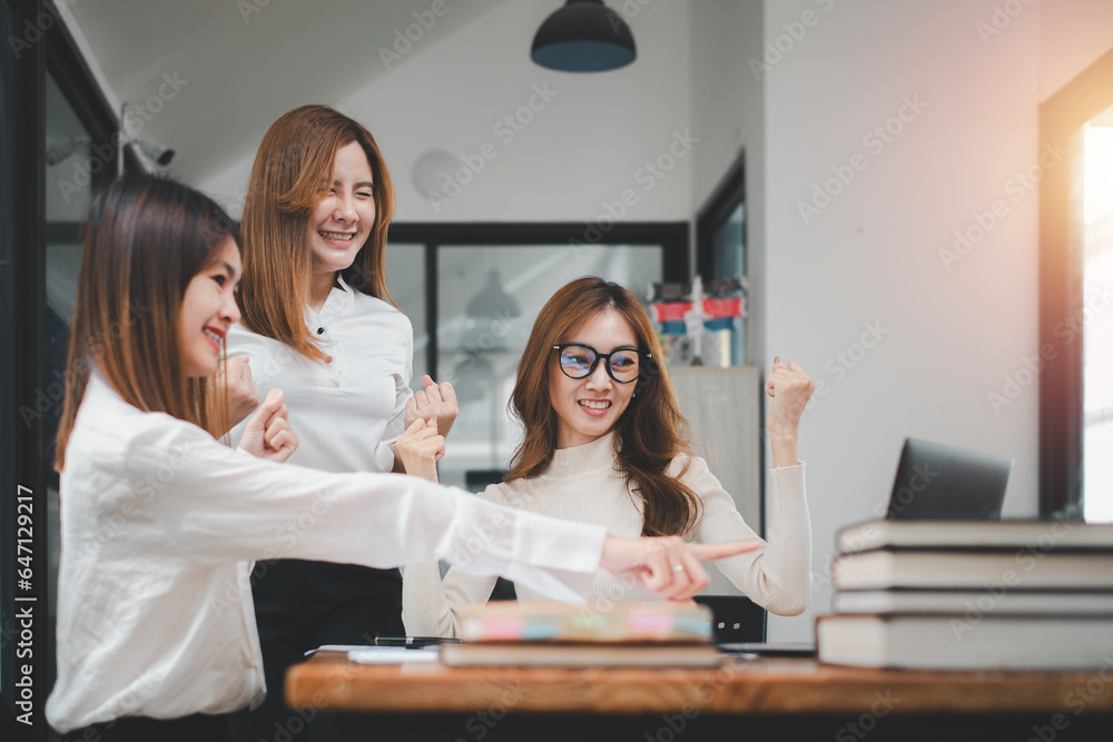 Three businesswomen show joyful expression of success at work smiling happily with a laptop computer in a modern office. Three businesswomen show joyful expression of success at work smiling happily with a laptop computer in a modern office.