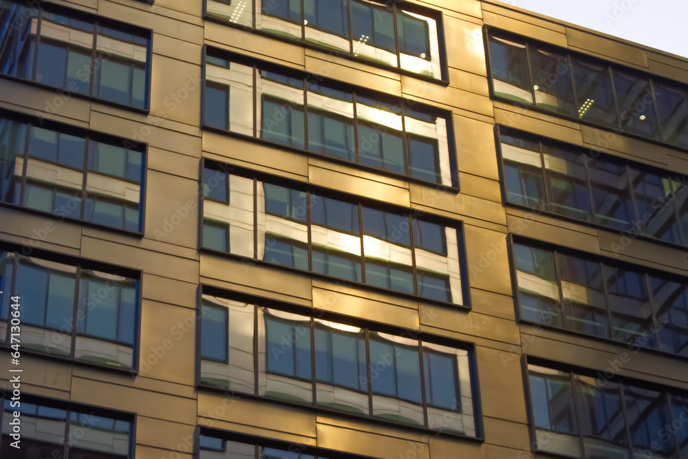 Modern glass facade of skyscraper during sunrise.