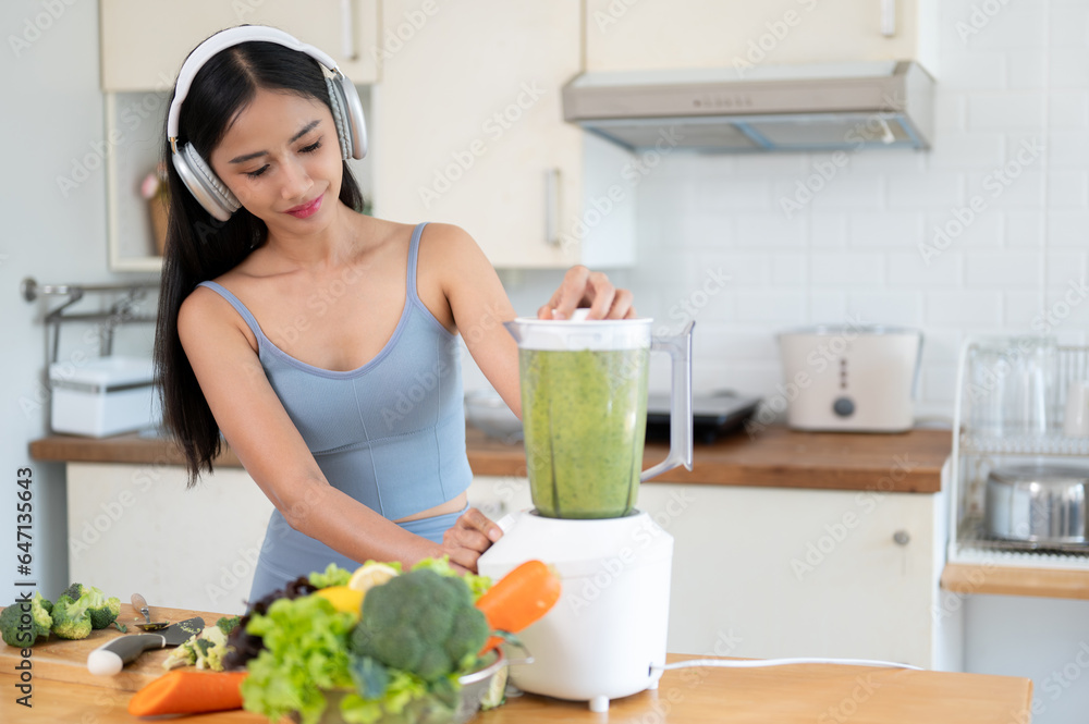 A fit and beautiful Asian woman in sportswear is making her healthy smoothie in the kitchen. A fit and beautiful Asian woman in sportswear is making her healthy smoothie in the kitchen.
