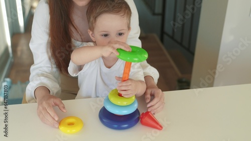 baby collects a toy pyramid. mom plays with son at home happy family. The development of fine motor skills in newborn child. family mom and baby play pyramid. preschool education in game kindergarten