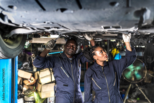 Black auto mechanic man and black woman working with car engine in auto repair garage