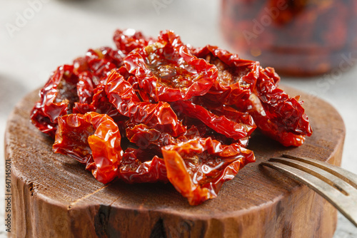 Close-up of homemade sun-dried tomatoes on a wooden board. Studio shot. photo