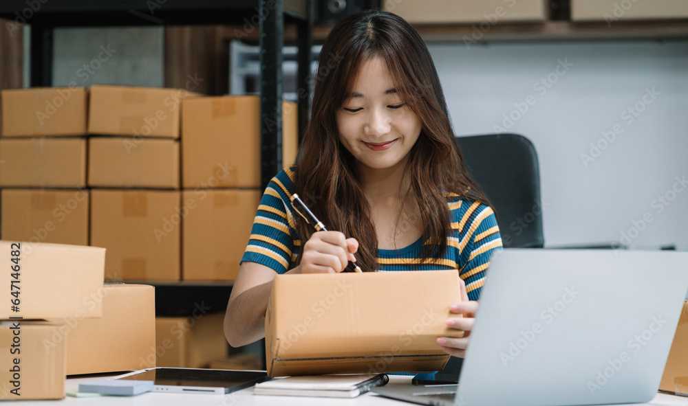 woman start up small business owner writing address on cardboard box at workplace.small business entrepreneur SME or freelance America woman working with box at home.
