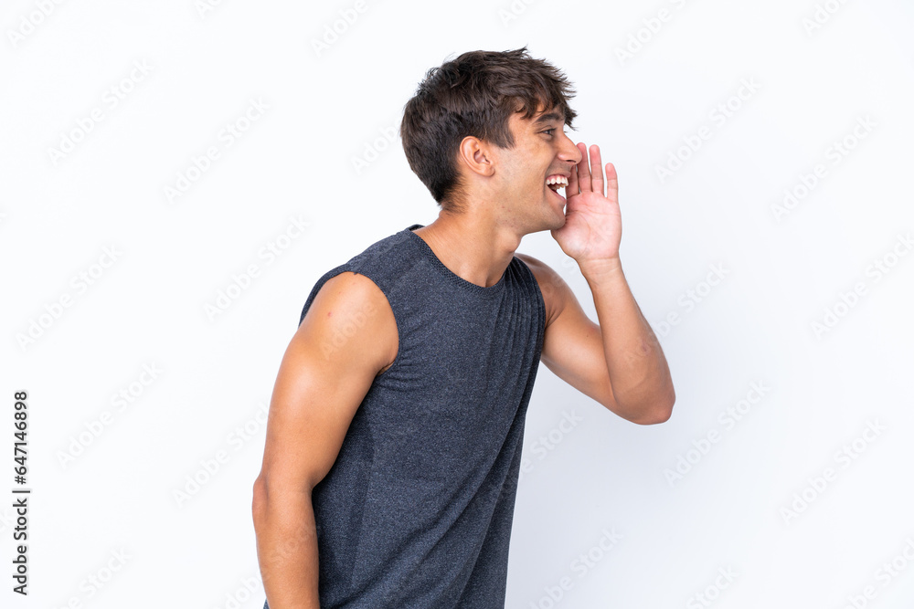 Young sport caucasian man isolated on white background shouting with mouth wide open to the lateral Young sport caucasian man isolated on white background shouting with mouth wide open to the lateral