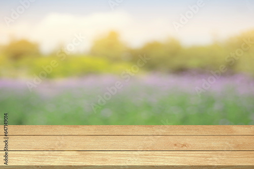 Empty wooden table top or counter blur flowers garden nature background in green trees spring park sunlight sky for template mock up and display montages product. Wood table plank background