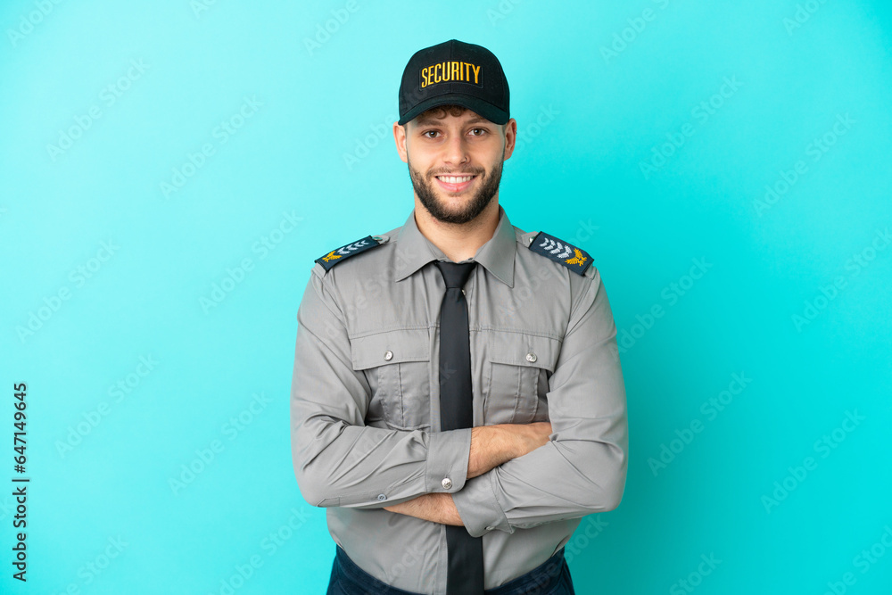 Young security man isolated on blue background keeping the arms crossed in frontal position Young security man isolated on blue background keeping the arms crossed in frontal position