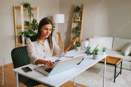 Portrait of young woman paying bills with credit card and laptop in office